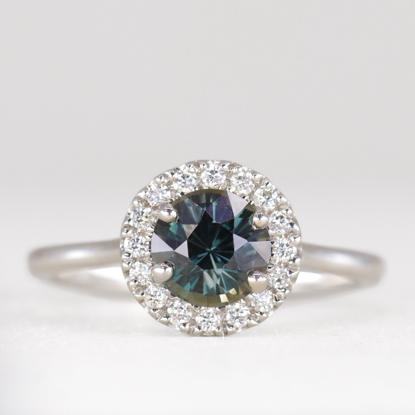 Round cut sapphire engagement ring with white diamond halo in platinum