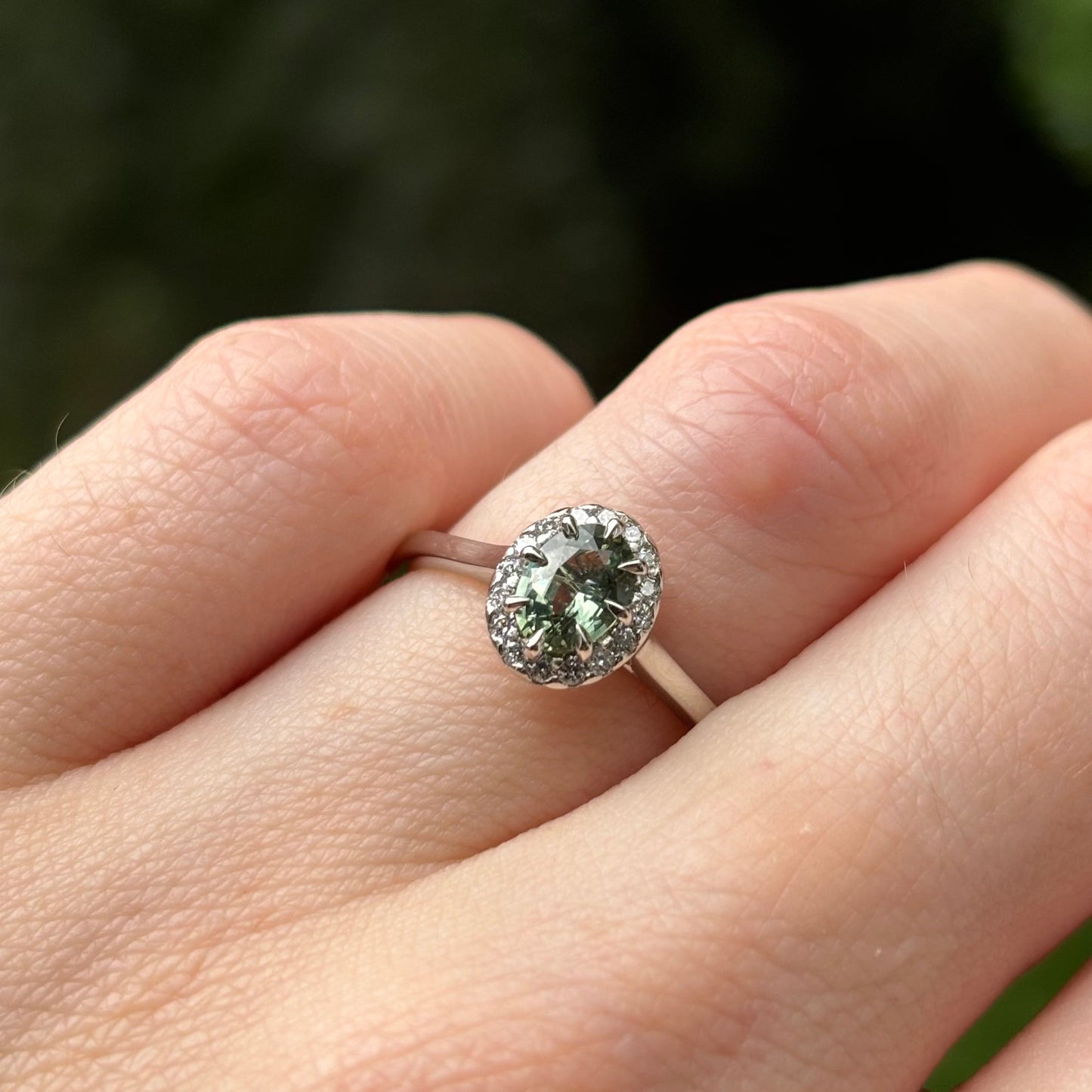 Oval cut teal sapphire with diamond halo engagement ring in platinum