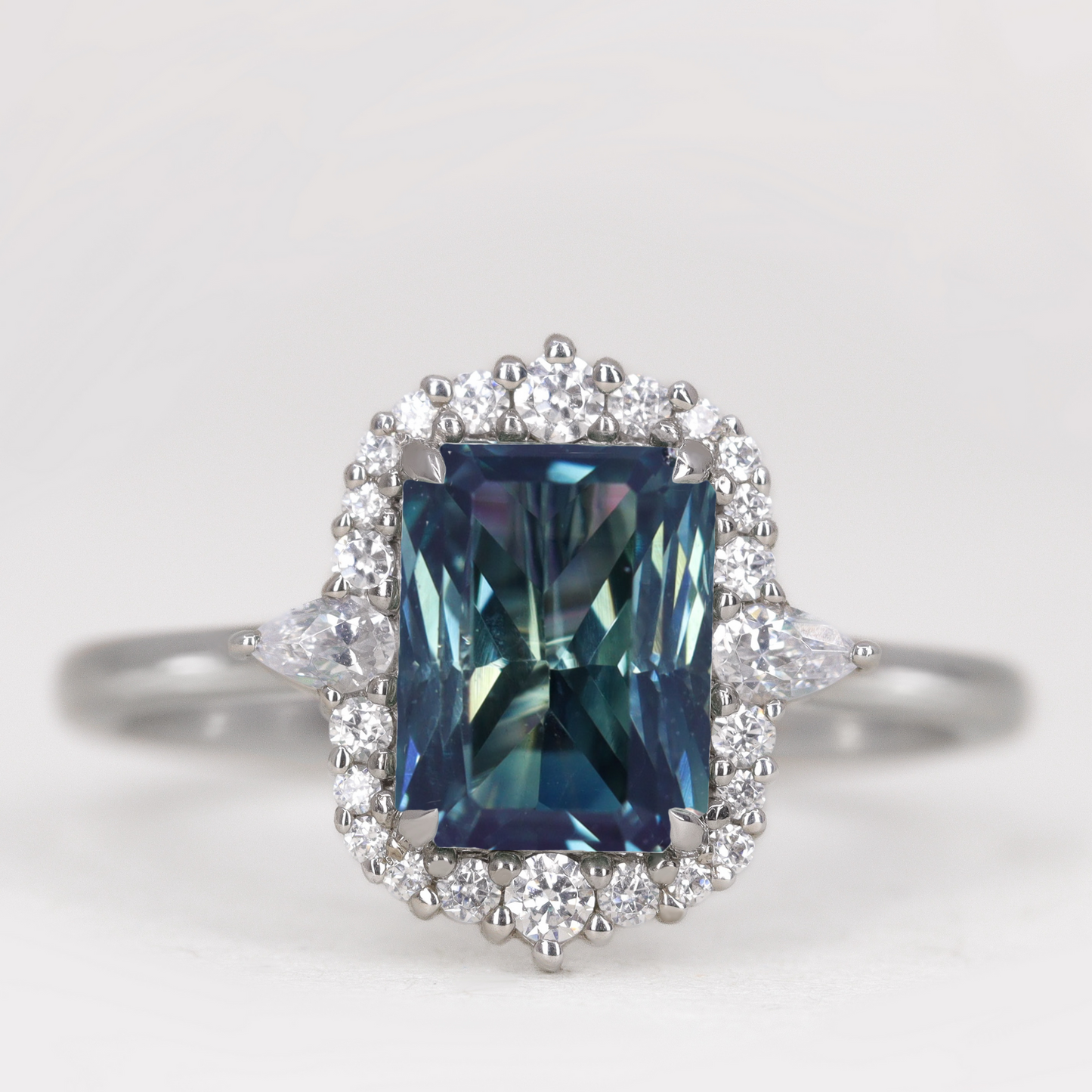 Emerald cut teal sapphire diamond halo engagement ring in platinum