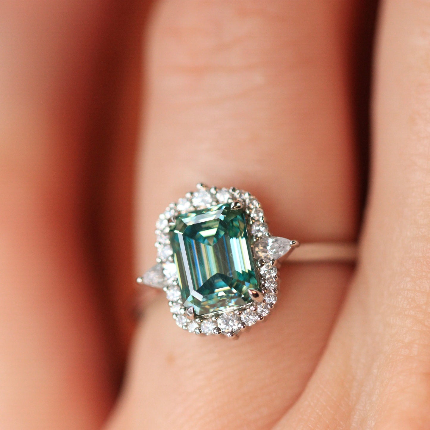 Emerald cut teal moissanite platinum engagement ring with diamond halo