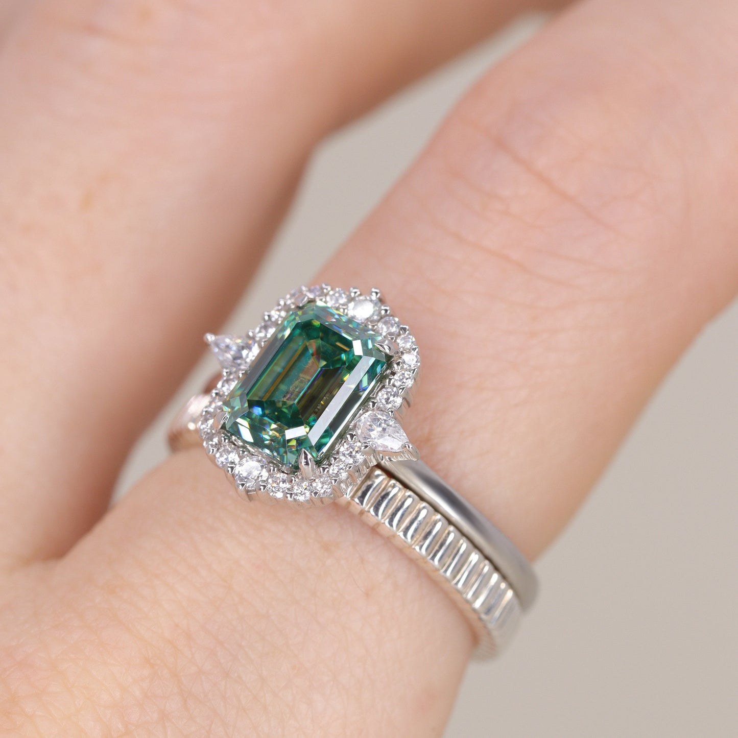 Emerald cut teal moissanite platinum engagement ring with diamond halo