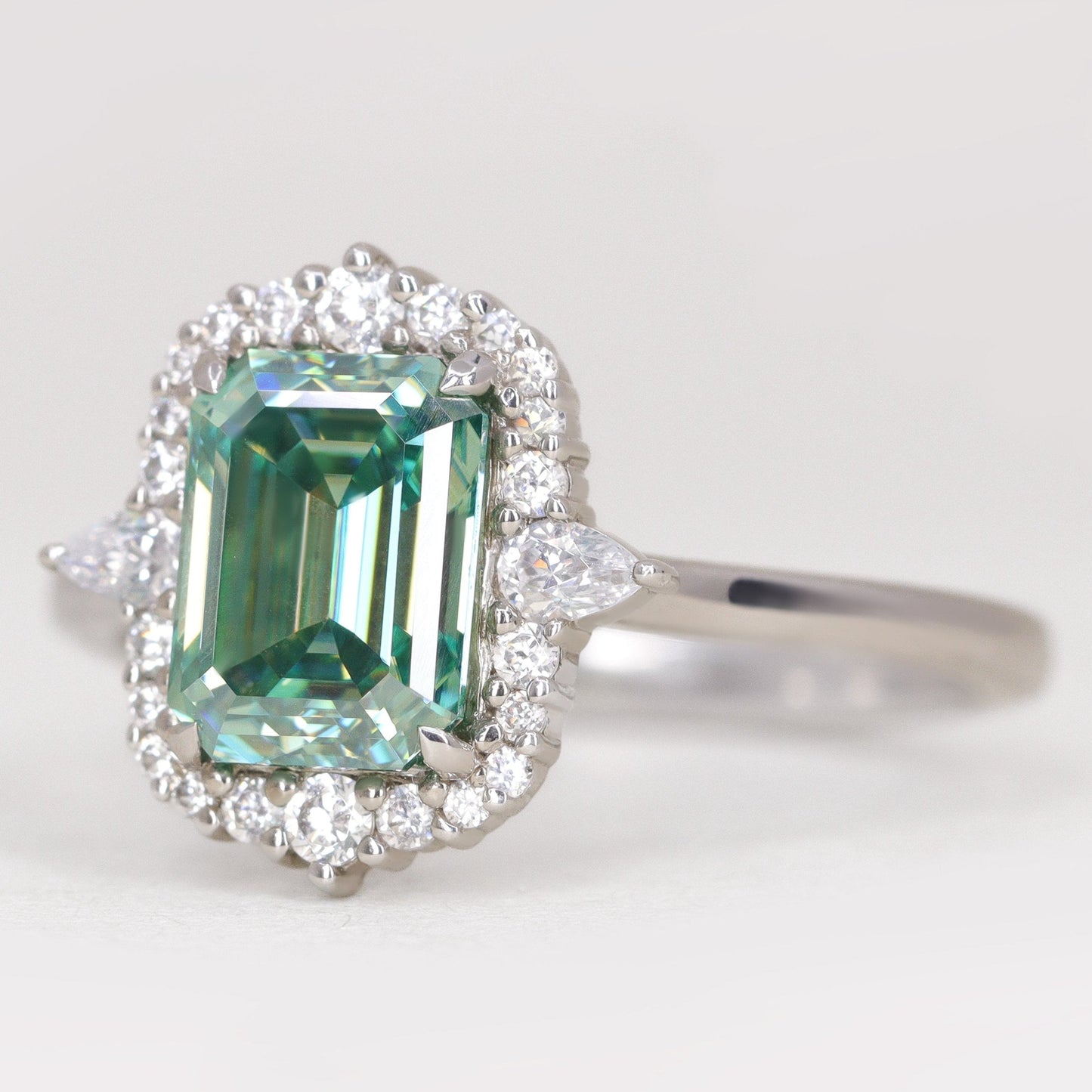 Emerald cut teal moissanite platinum engagement ring with diamond halo