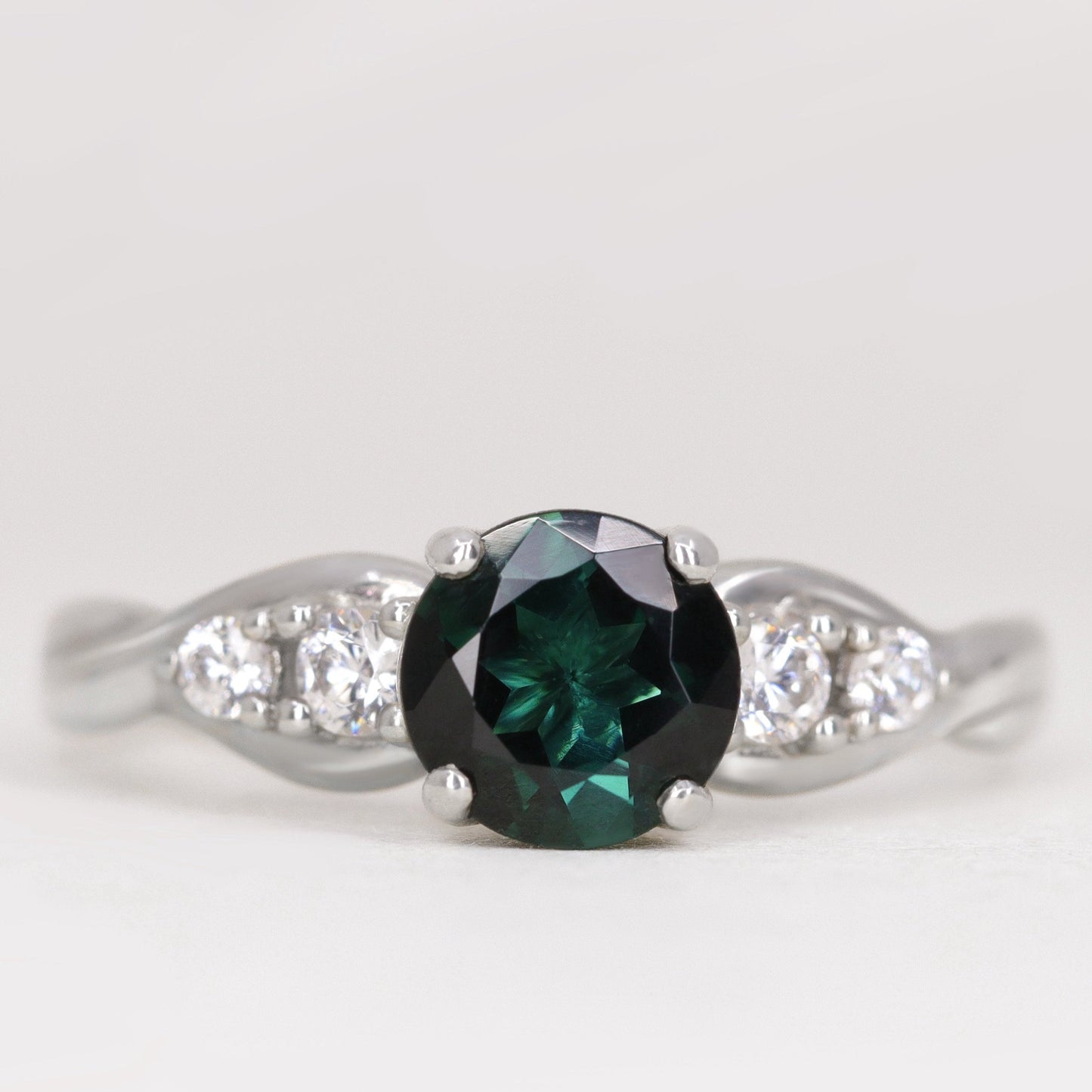 Round cut teal sapphire and white diamond engagement ring in platinum