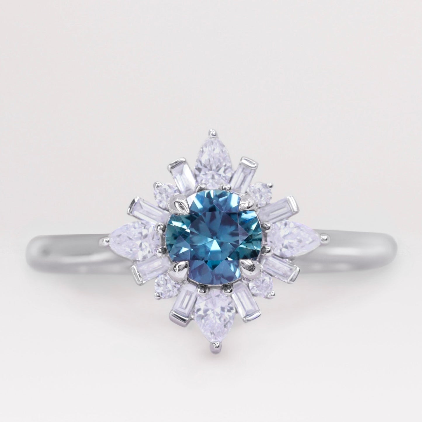 Round cut teal sapphire and white diamond engagement ring in platinum