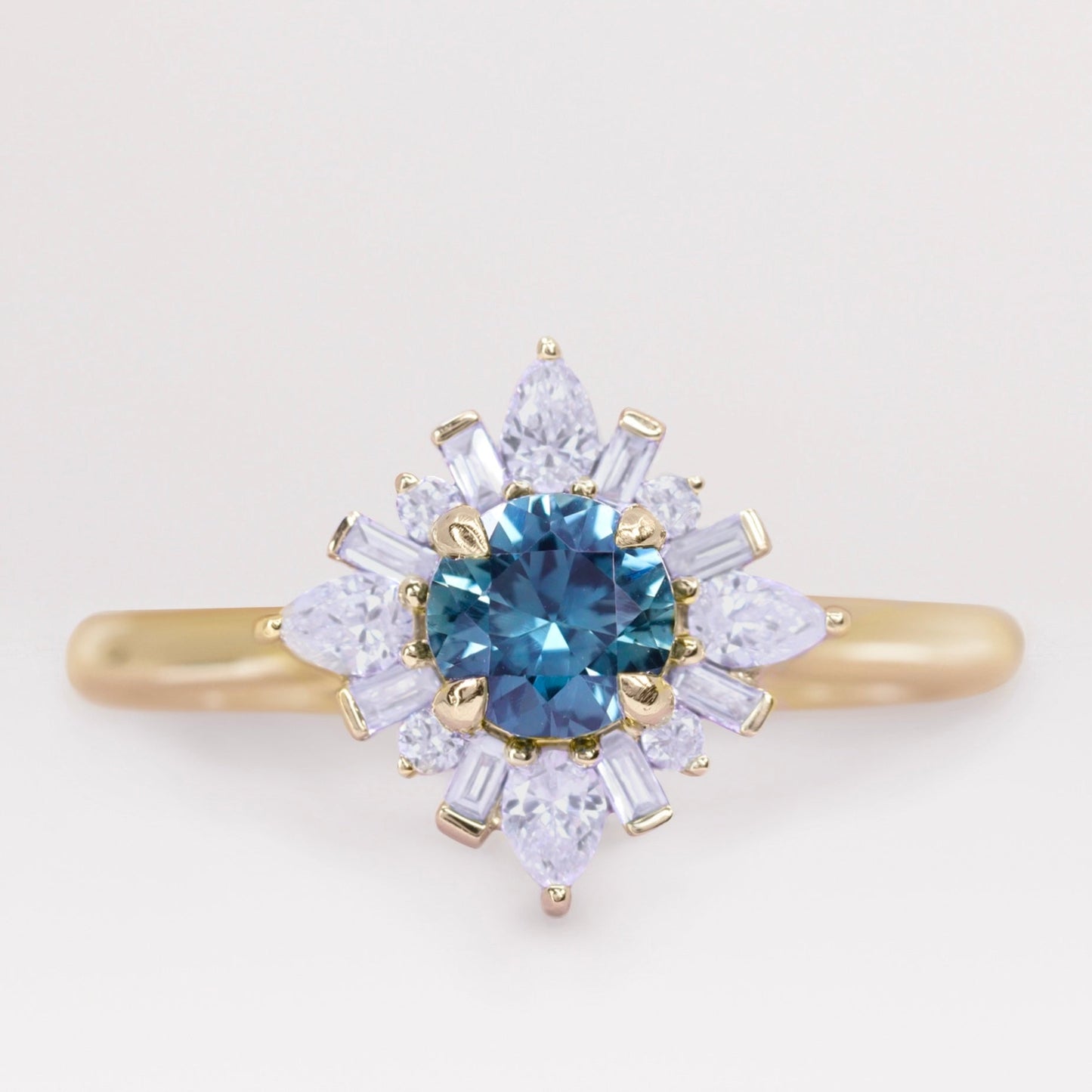 Round cut teal sapphire and white diamond engagement ring in yellow gold